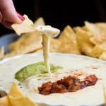 super easy queso blanco dip with a chip scooping out a serving.