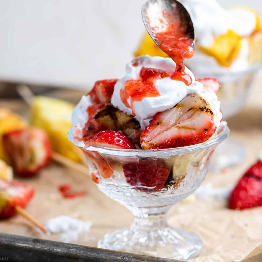 Grilled strawberry shortcake parfait with spoon drizzling strawberry juice on top 