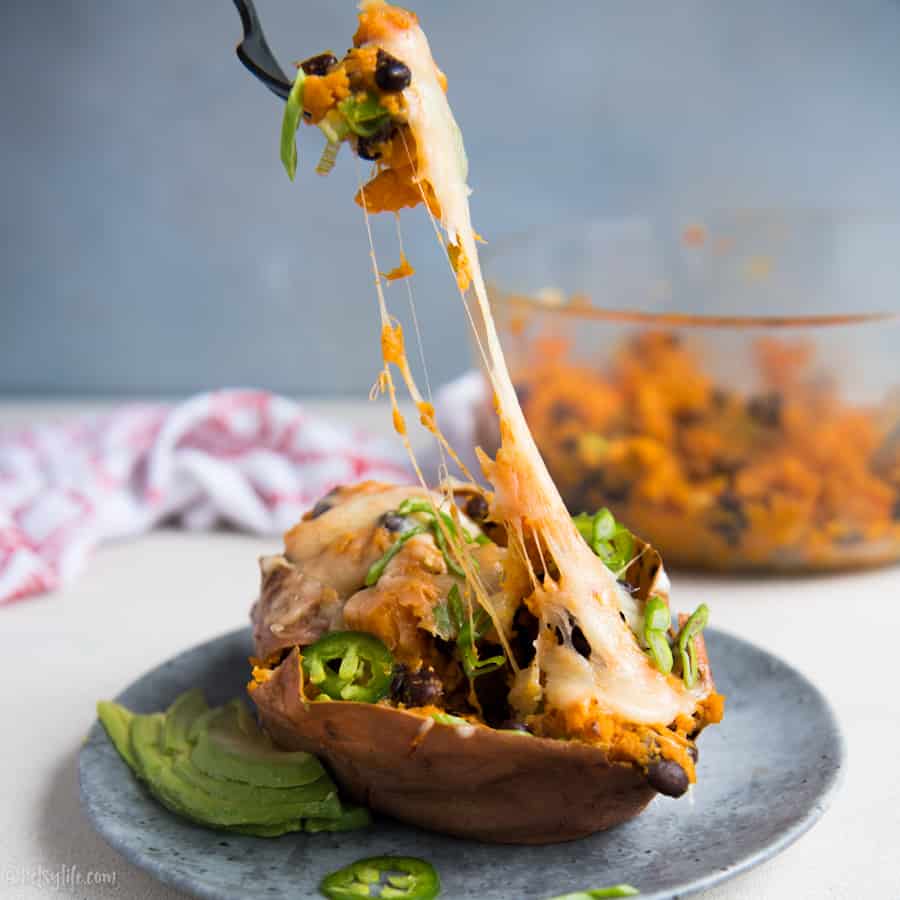 Twice baked sweet potato with a fork pulling out a cheesy bite