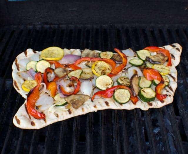 uncooked veggie pizza on grill rack
