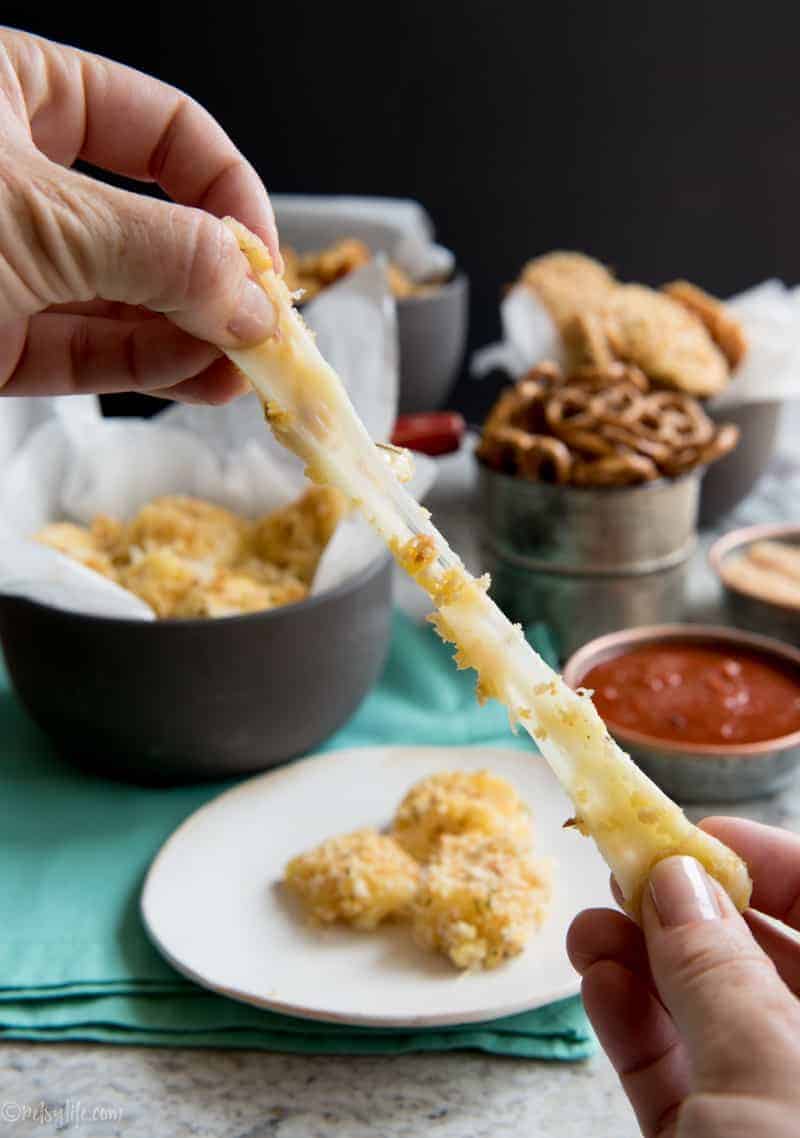 hands stretching a cheesy baked mozzarella stick 