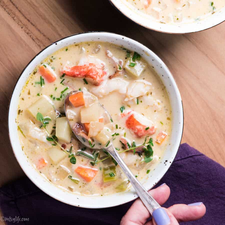 Spoon dipping into a bowl of potato, bacon and lobster chowder