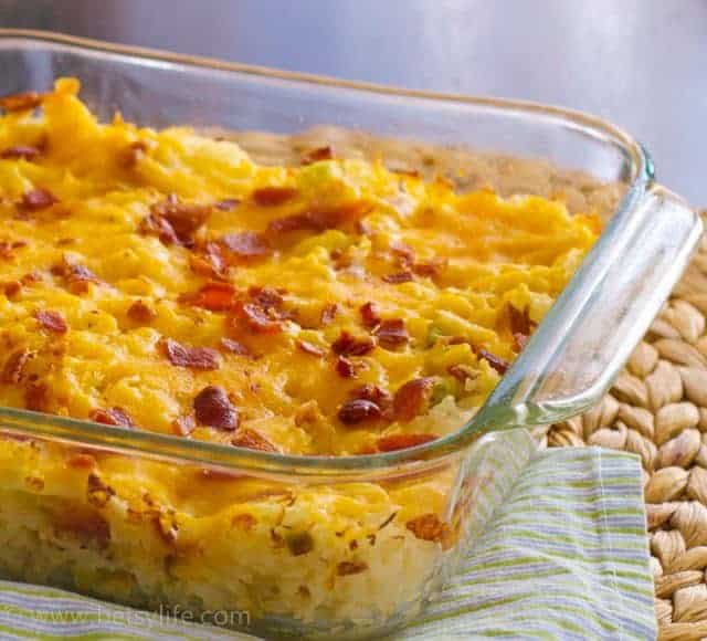 glass casserole dish of baked potato casserole topped with cheese and bacon