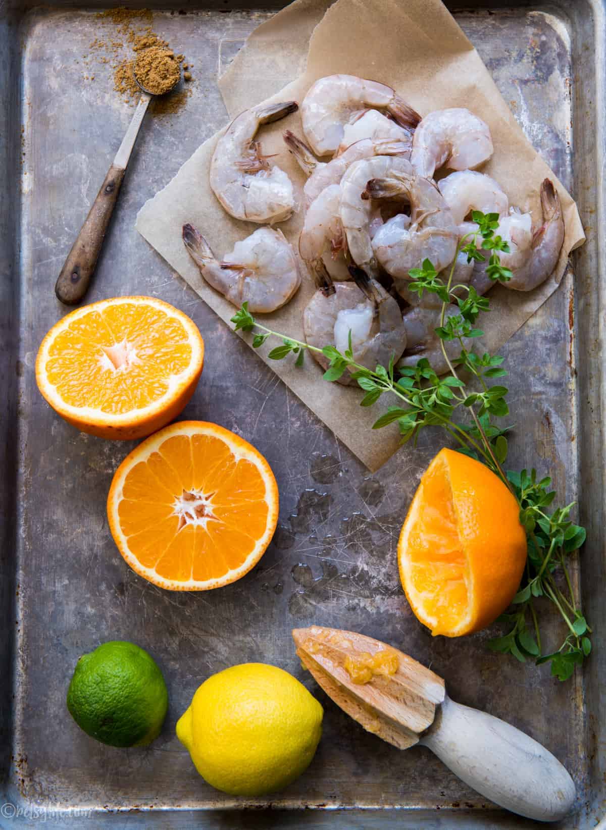 metal tray with raw shrimp, citrus, fresh and dried herbs