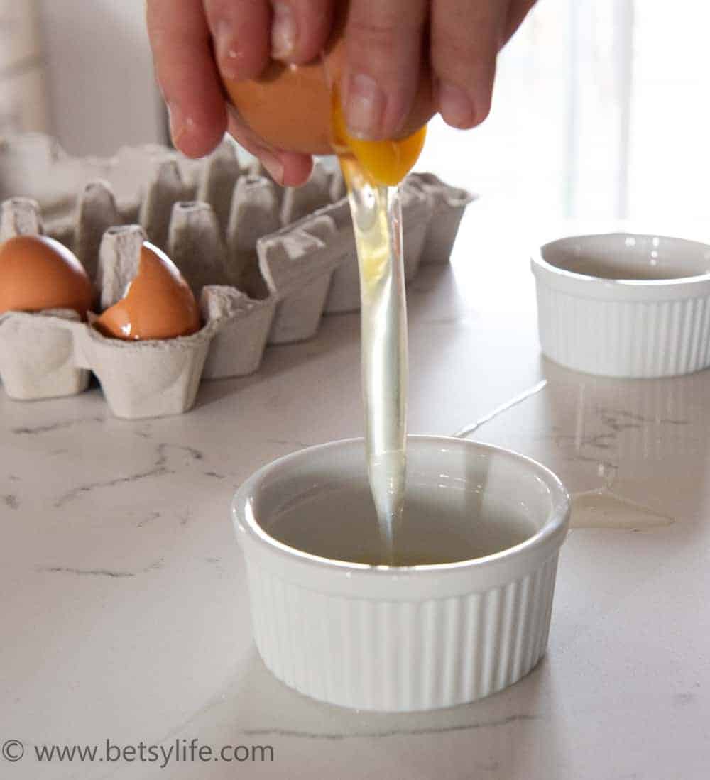 egg cracking into a small white ramekin