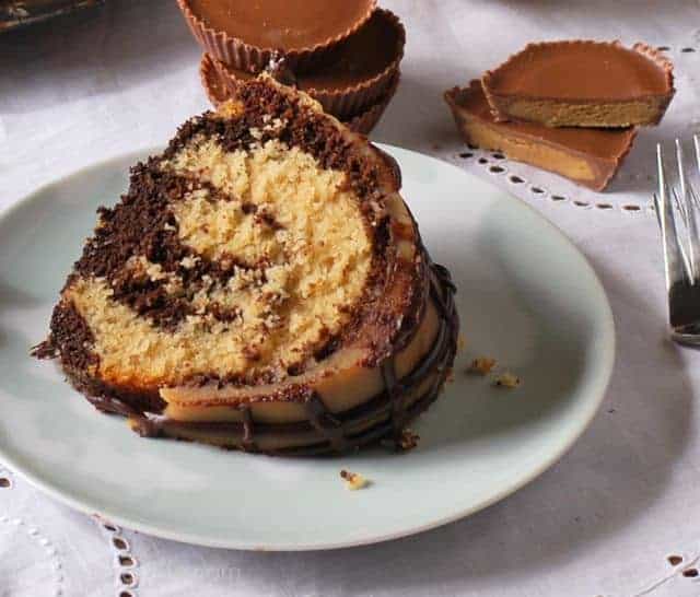 slice of chocolate swirl cake on light plate with peanut butter cups in background