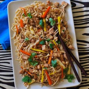 rectangular white plate of noodles meat chunks and vegetables