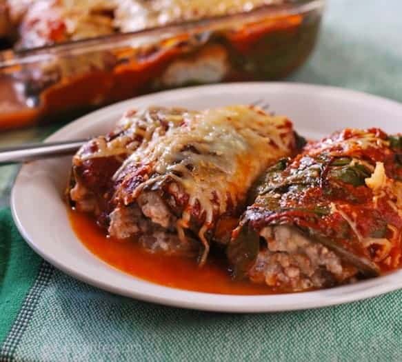 close up of serving of rainbow chard wrapped cannelloni covered in red sauce and melted cheese