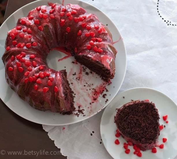 devils food bundt cake with a cinnamon glaze on a white plate with a slice removed on a plate next to it. 