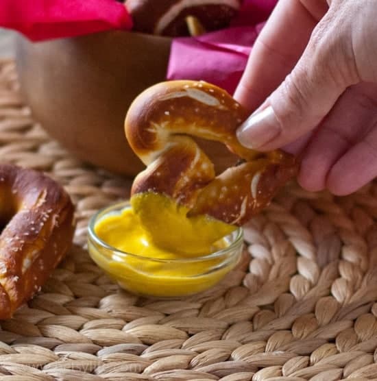 homemade heart shaped pretzel dipping into a small dish of mustard 
