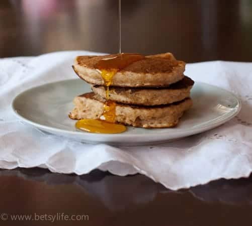 stack of 3 pancakes on plate with action of syrup drizzle