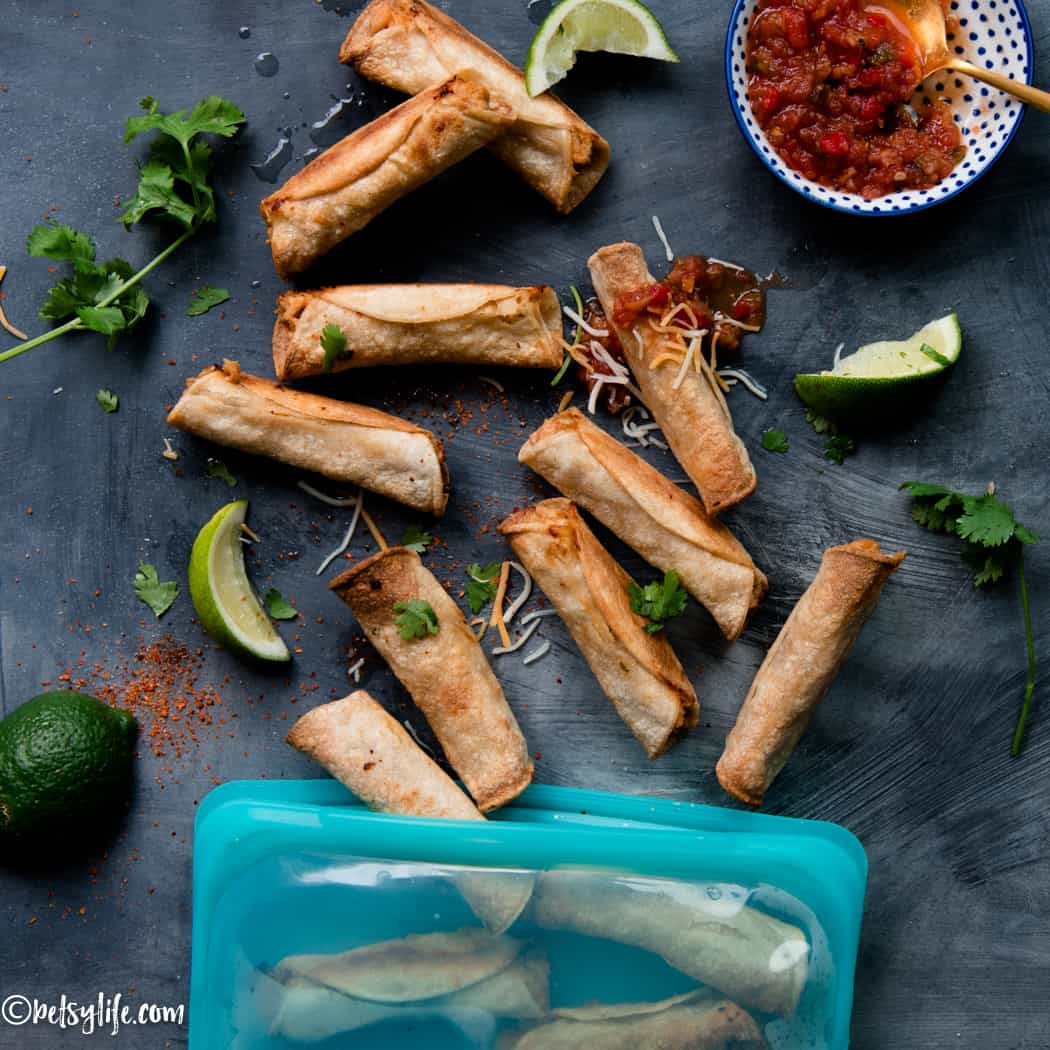 crispy taquitos next to a freezer bag topped with salsa, cilantro and shredded cheese