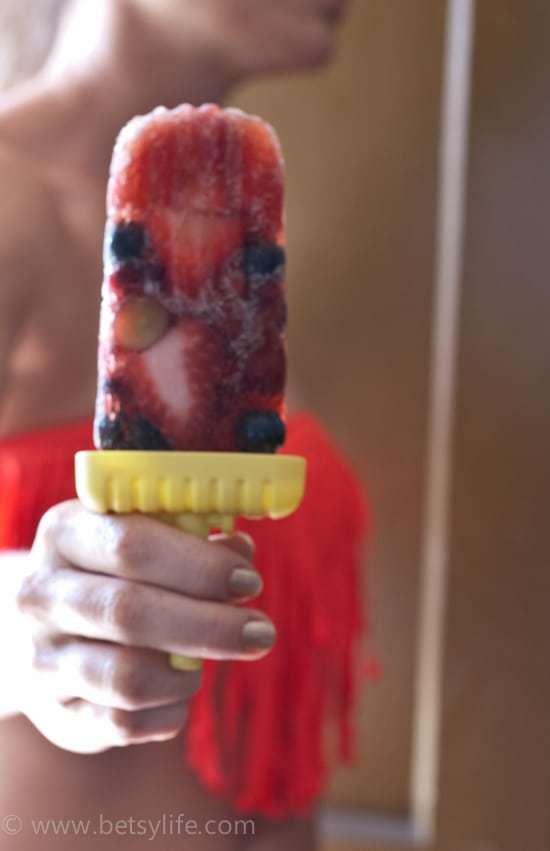 woman holding popsicle with berries inside