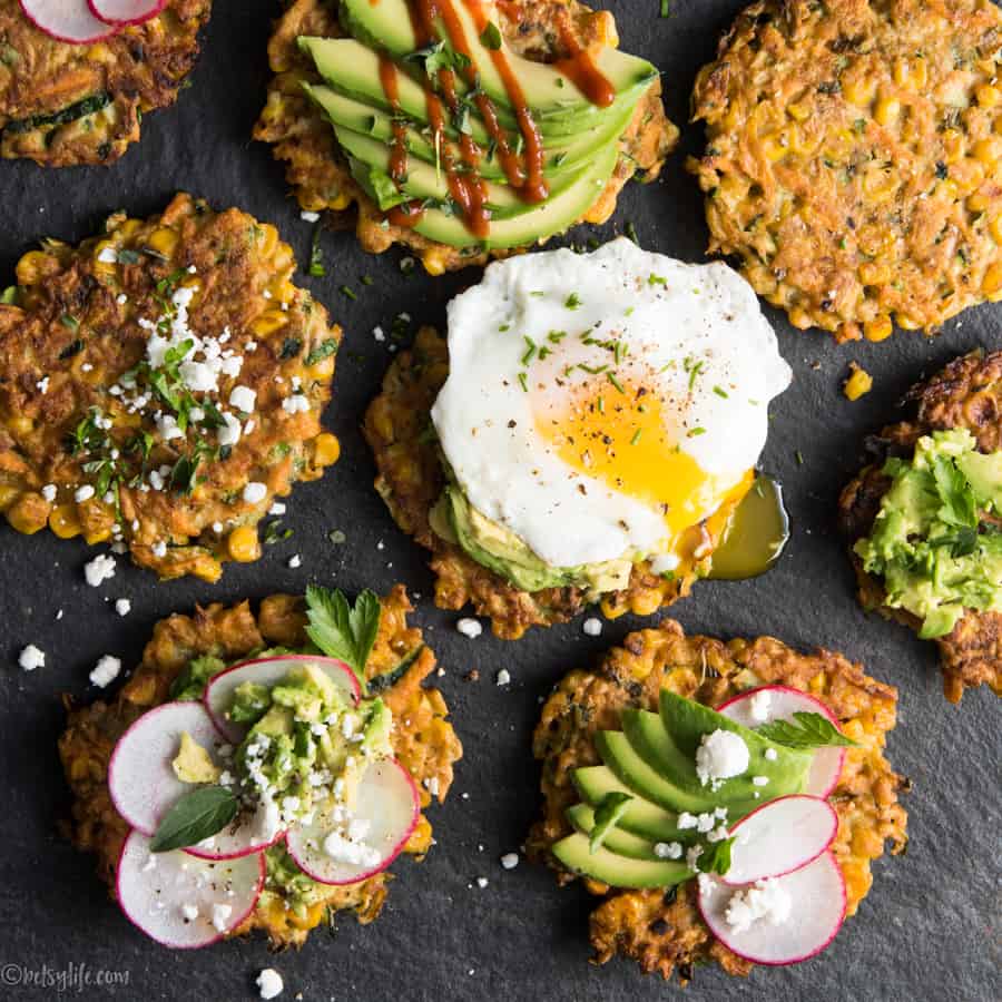 Detail of zucchini, carrot and corn fritters topped with eggs, avocado, hot sauce and radishes 