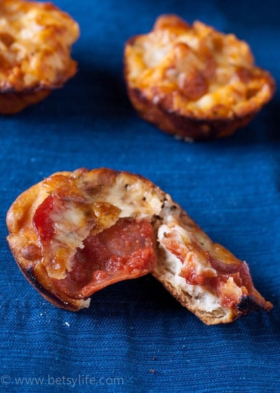 Close up of pepperoni inside of a pulled apart snack bite on a blue background 