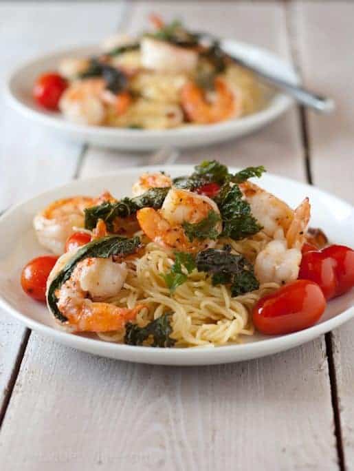 pasta with shrimp kale and whole tomatoes on white plates