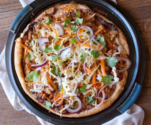 BBQ Chicken Pizza topped with shredded cabbage, thinly sliced red onions, shredded carrots and cilantro leaves