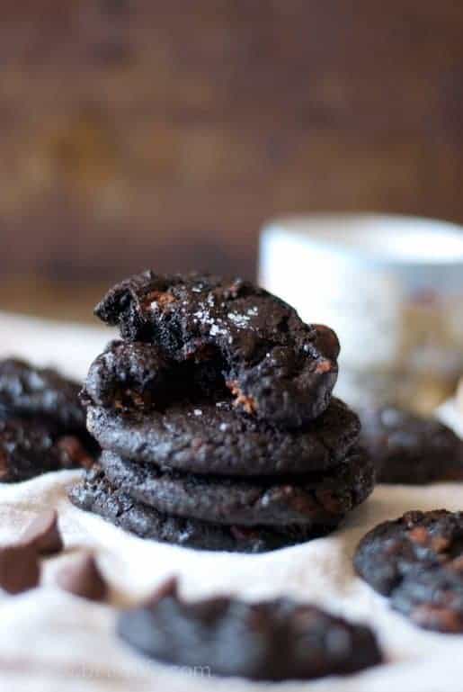 stack of Dark Chocolate Salted Caramel Cookies. Top cookie broken in half to expose the inside 