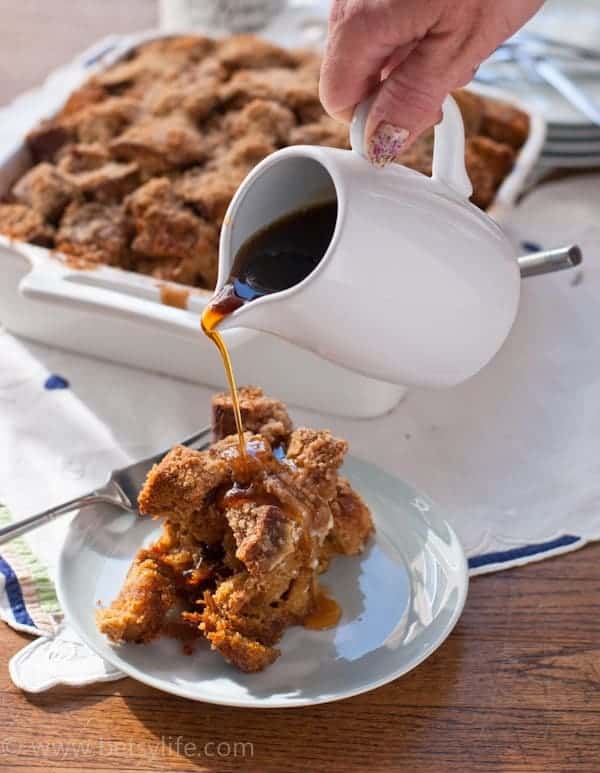 Gingerbread French Toast Casserole serving with hand pouring syrup from a small white pitcher 
