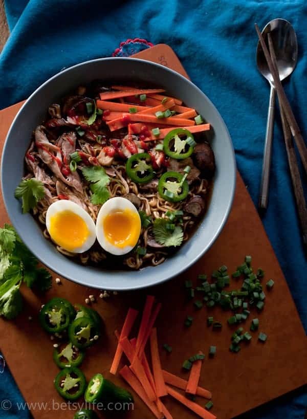 blue bowl of carrot, jalapeno, soft-boiled egg, and meat on cutting board