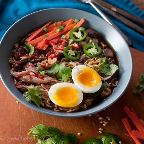blue bowl of meat with carrots and jalapeno peppers and soft-cooked egg