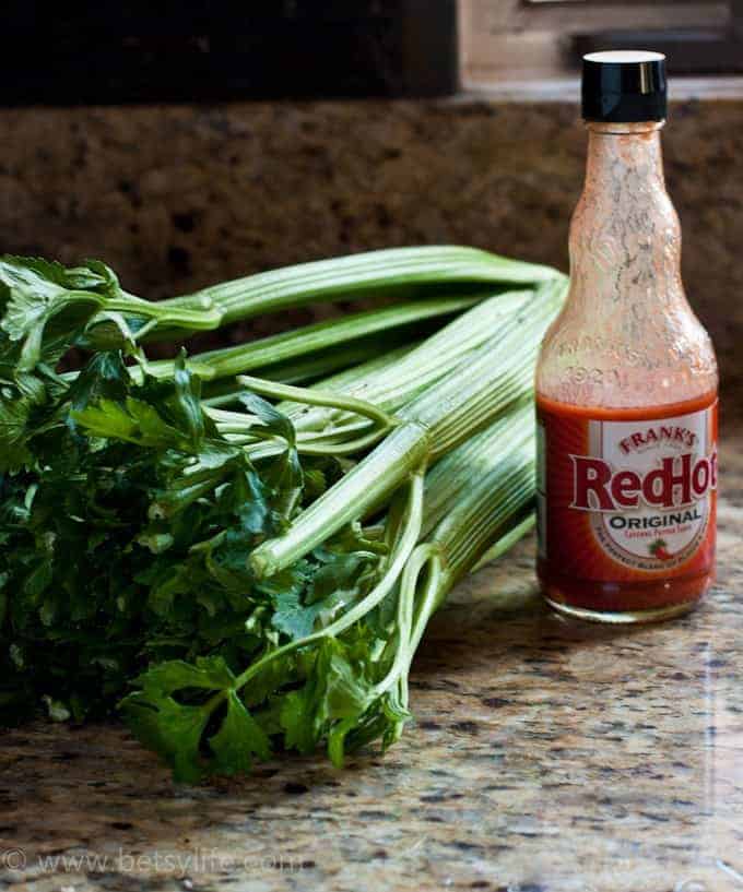 bunch of celery next to bottle of Frank's hot sauce