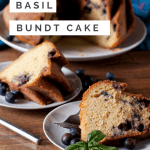 Basil blueberry bundt cake with two slices cut out on separate plates in the foreground with fresh blueberries scattered around