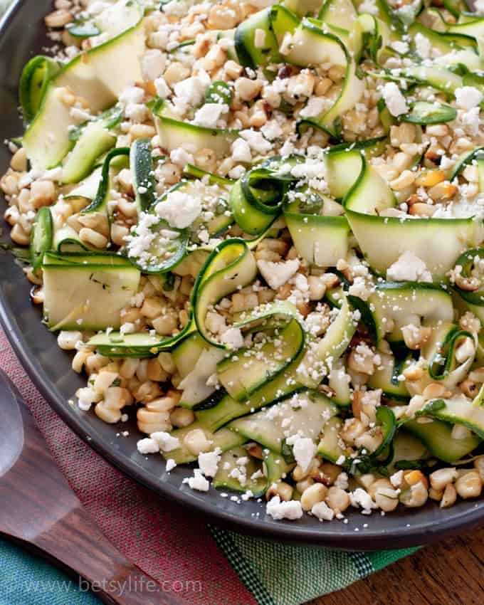 Grilled Corn and Zucchini Salad topped with crumbled feta cheese on a brown oval shaped plate