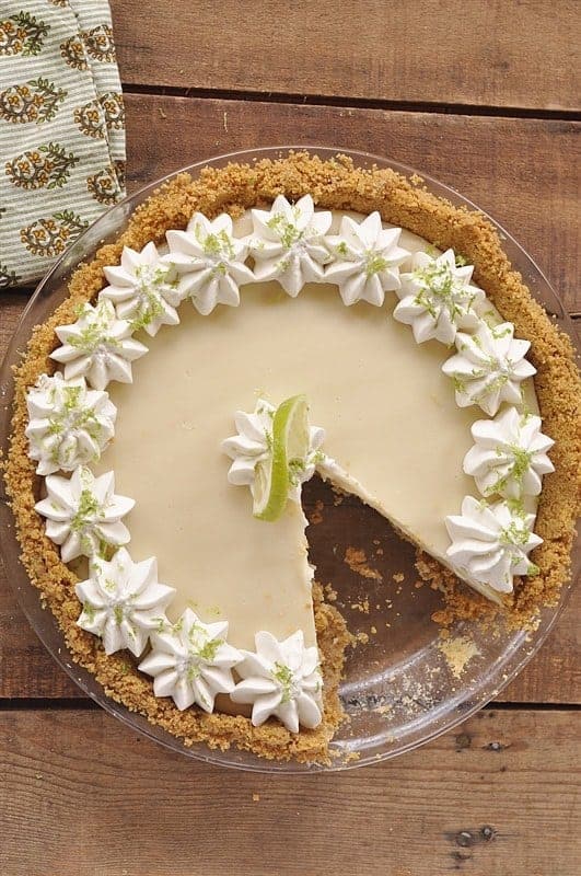 Overhead view of best key lime pie recipe with a slice removed on a wooden background
