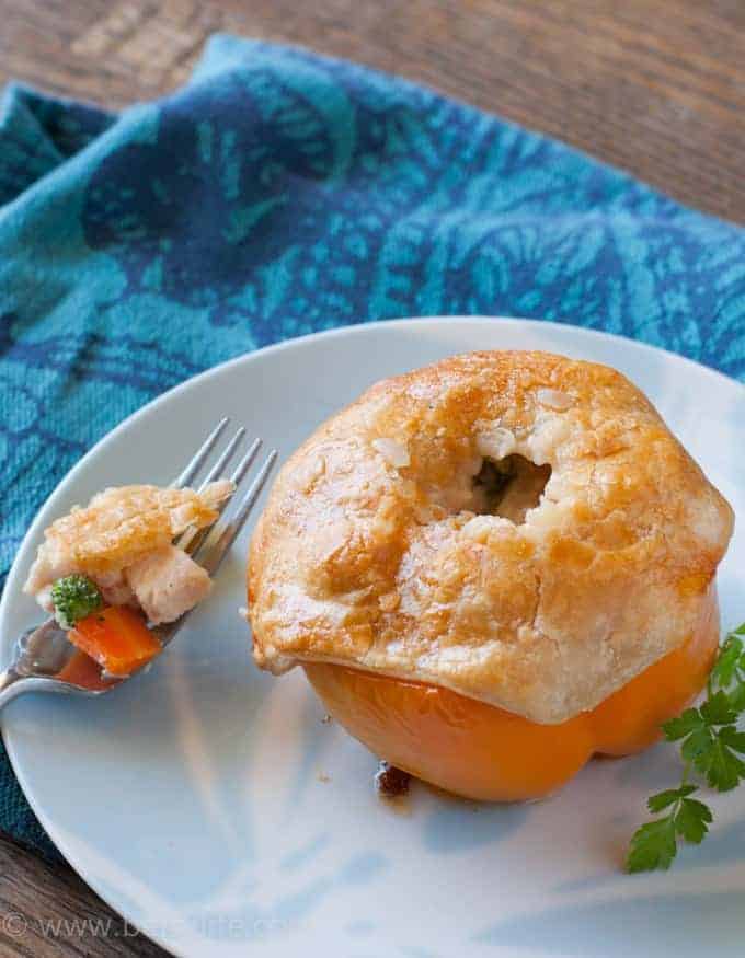 Chicken Pot Pie Stuffed Pepper on a light blue plate sitting on a dark blue patterned napkin. Fork with a bite on the side of the plate. 