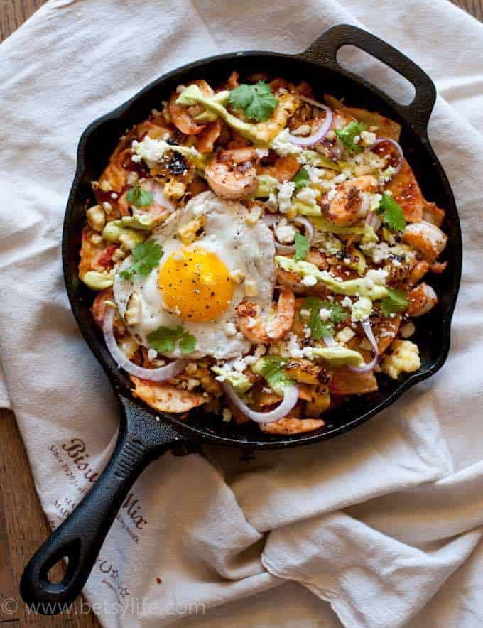 Skillet of grilled corn and shrimp chilaquiles topped with a fried egg