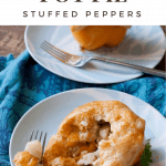 Two Chicken Pot Pie Stuffed Peppers on light blue plates with forks. Background one is whole and out of focus. Foreground is cut into with filling spilling out