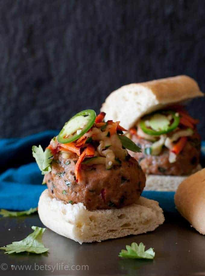 Banh mi meatball slider open faced on a roll, topped with carrot slaw and a thinly sliced jalapeno. 