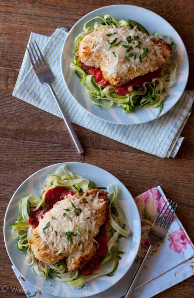 Two plates of Baked Chicken Parmesan Over Zucchini Noodles