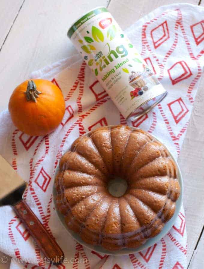 pumpkin spice bundt cake next to a small pumpkin and a container of zing baking blend 