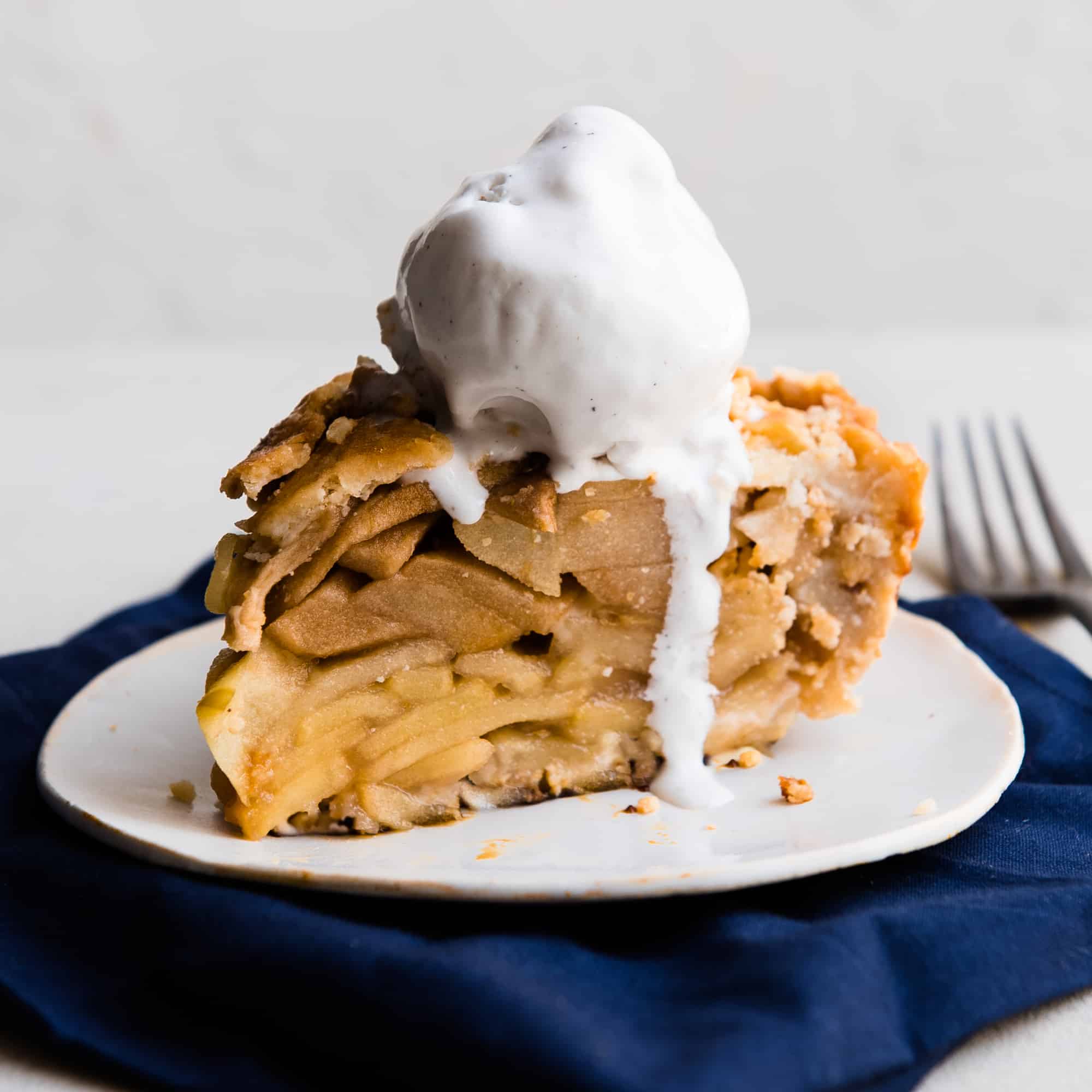 Slice of apple pie with a scoop of vanilla ice cream melting on top 