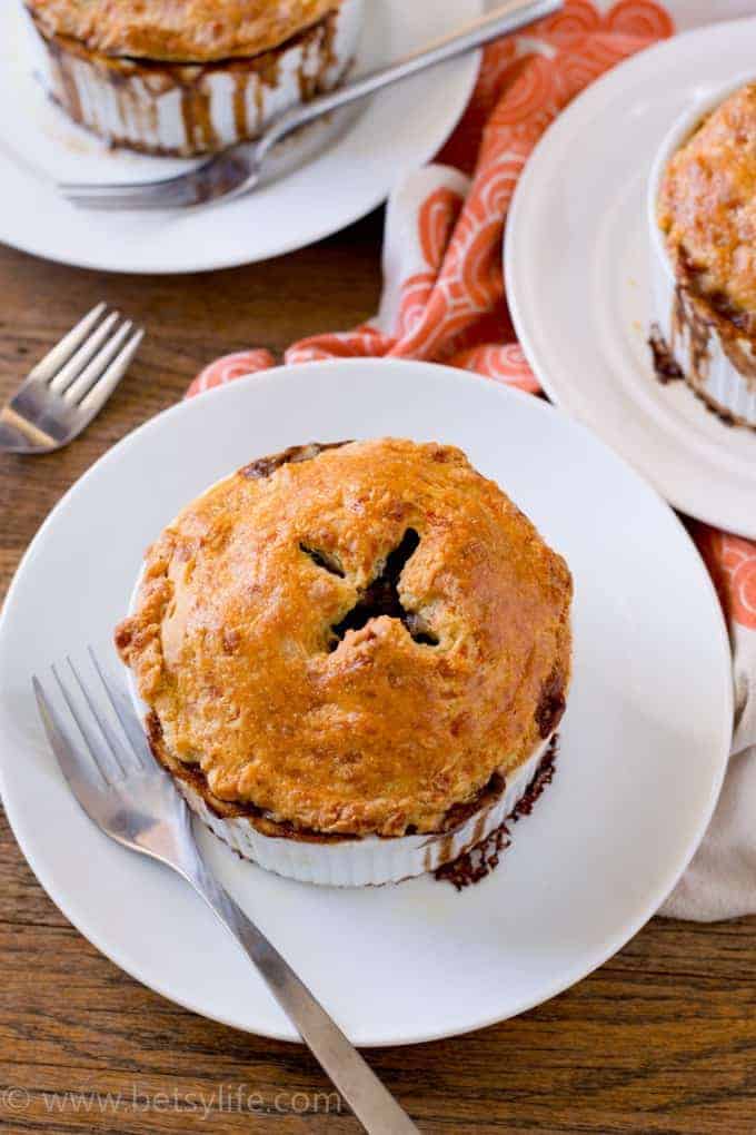 Close up of an individual serving, fully cooked beef pot pie with a cheddar crust on a plate with a fork