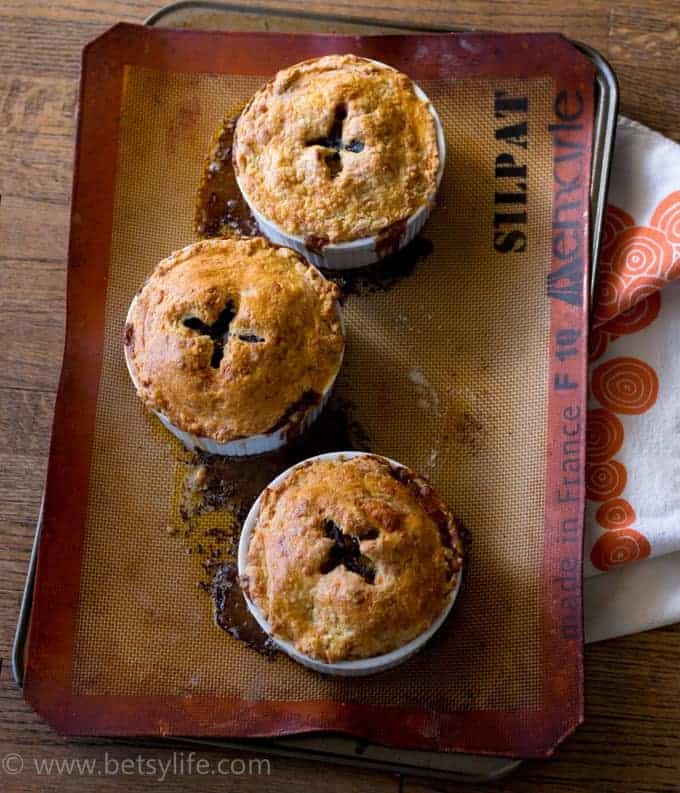 three fully cooked individual pot pies on a baking sheet lined with a non-stick mat