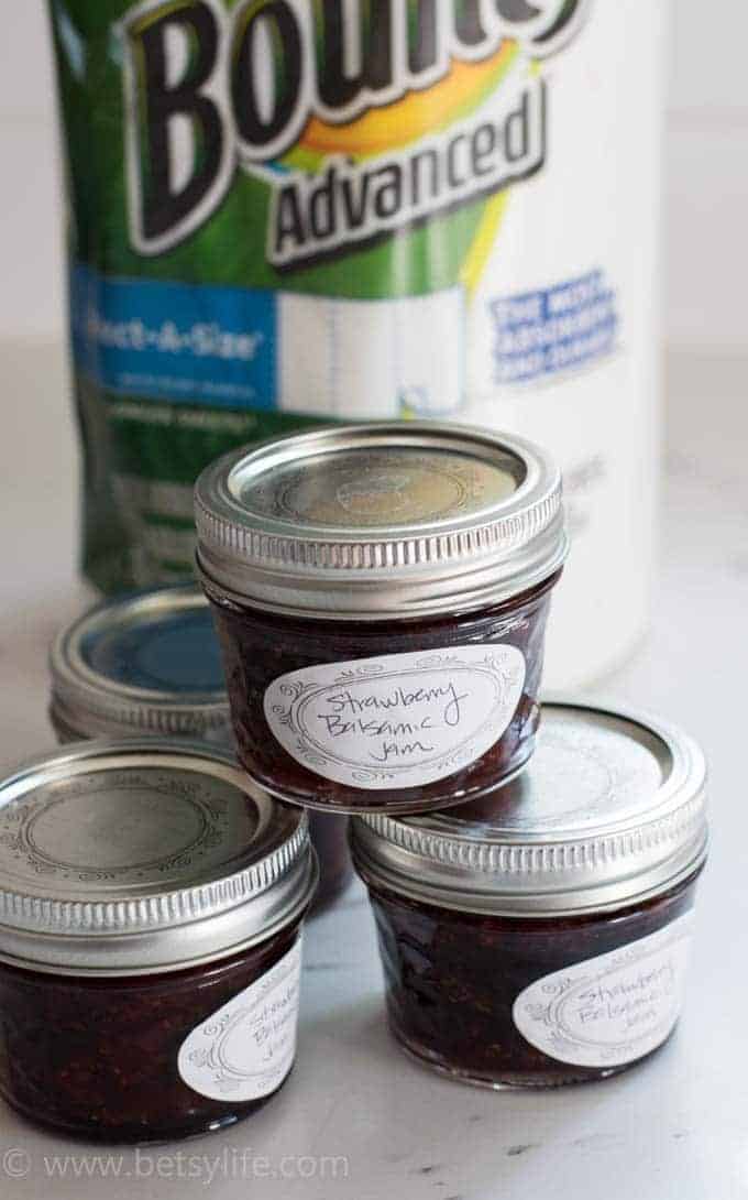 homemade strawberry jam jars stacked in a pyramid with a roll of Bounty paper towels out of focus in the background