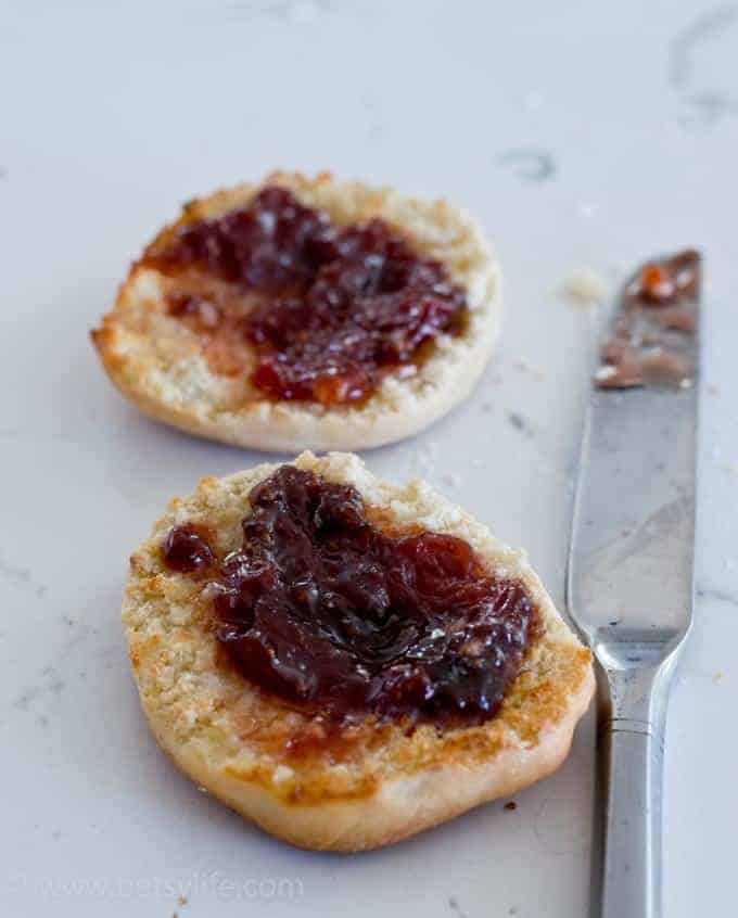 Two halves of an english muffin spread with jam
