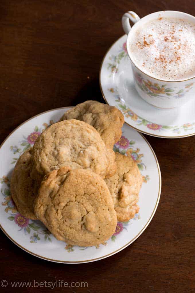 chai spiced peanut butter chip cookies on a floral printed plate with a latte on a wood surface