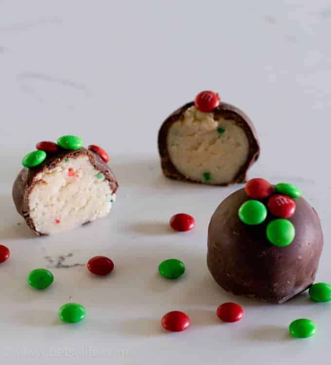 balls of white cake batter covered in chocolate with red and green candy