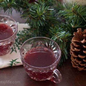 Punch glass of Red Wine Holiday Punch surrounded by pine garland