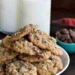 Salted Peanut Butter Cup Cookies heaped on a white plate with two glasses of milk in the background