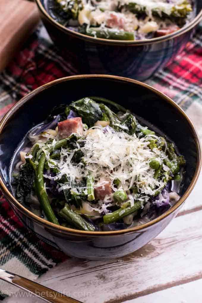 healthy minestrone soup in a blue bowl with grated cheese on top 