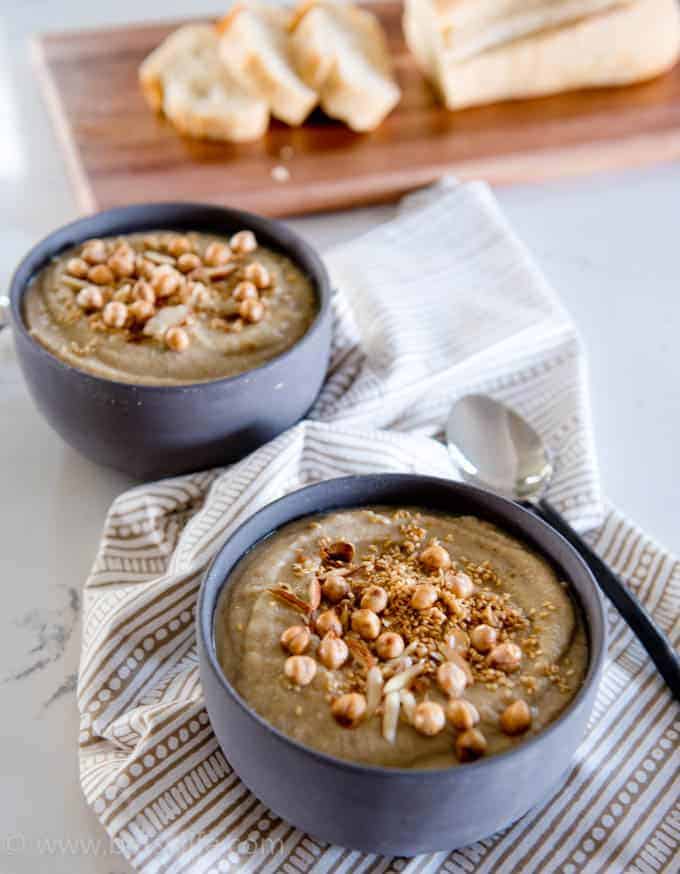 Healthy Cauliflower Soup in gray bowls with bread in the background