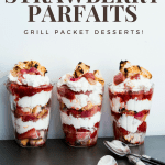 three layered rhubarb strawberry parfaits in clear glasses in a row. Layers of grilled angel food cake, grilled strawberries, grilled rhubarb and whipped cream