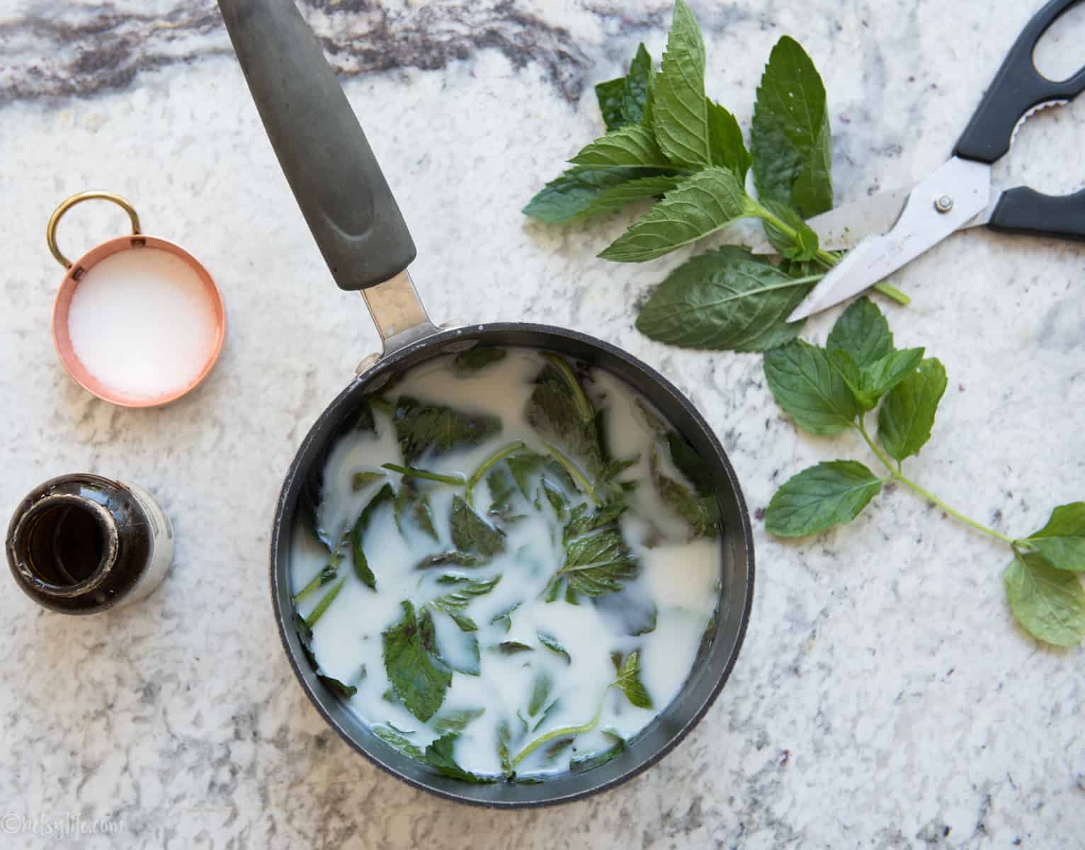 pot with fresh mint steeping in milk on a marble countertop