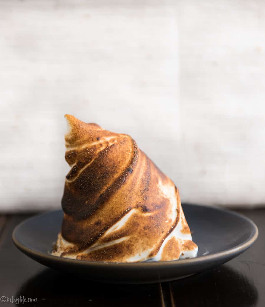 golden brown individual baked alaska on a gray plate 