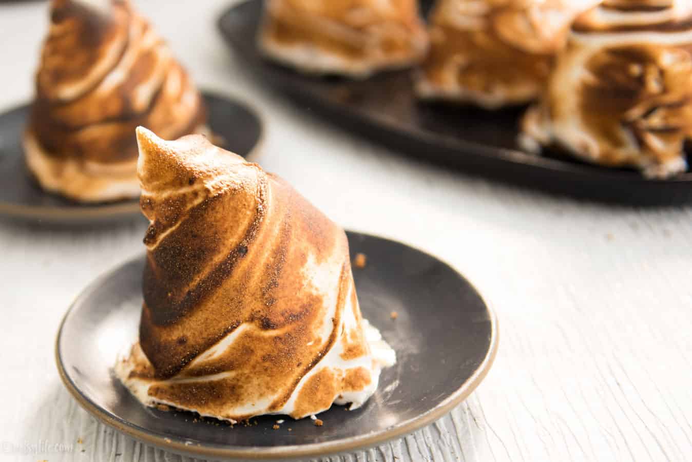 golden brown toasted individual baked alaska on a gray plate